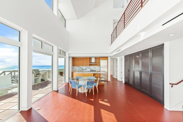 dining space featuring a water view, a high ceiling, and a view of the beach