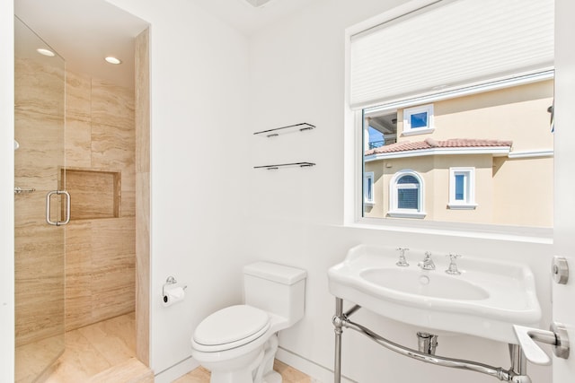 bathroom featuring toilet, a shower with door, and sink