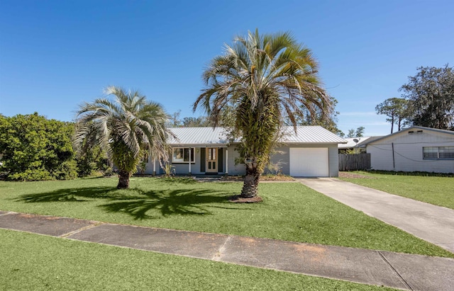 ranch-style house with concrete driveway, metal roof, and a front lawn