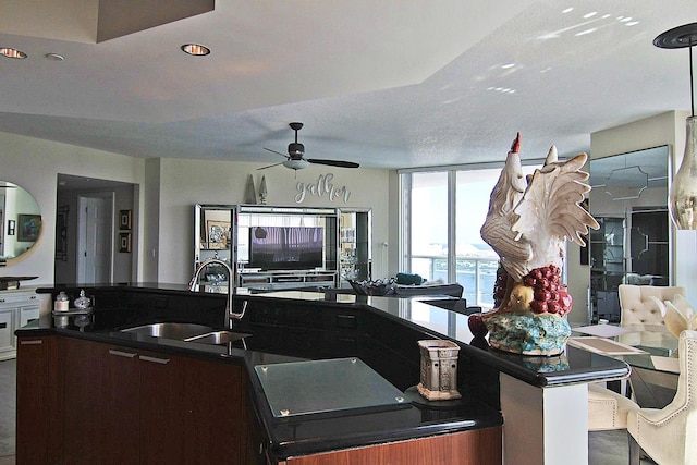 kitchen with ceiling fan, a kitchen island with sink, sink, and a textured ceiling