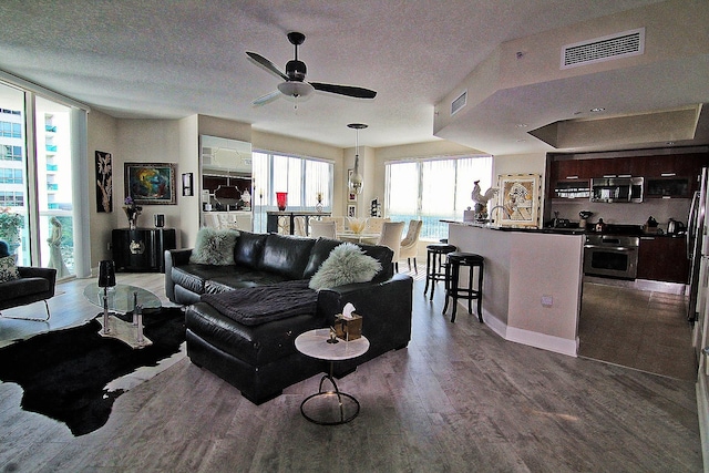 living room featuring ceiling fan, sink, hardwood / wood-style floors, and a textured ceiling