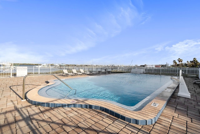 view of pool featuring a water view and a patio area