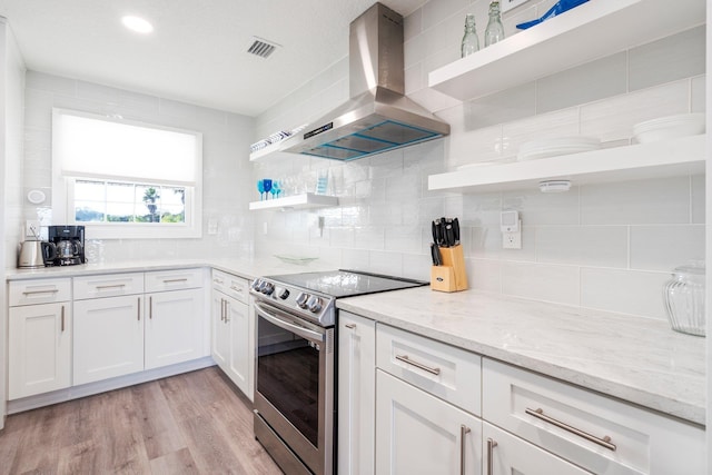 kitchen with extractor fan, white cabinets, electric range, light stone countertops, and light wood-type flooring