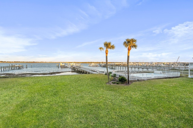 view of dock with a lawn and a water view