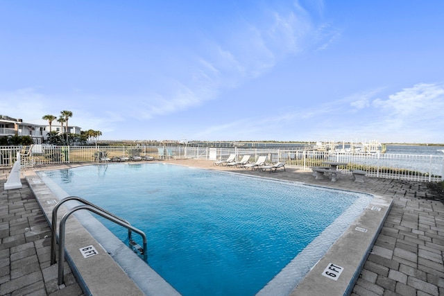 view of swimming pool with a water view and a patio area