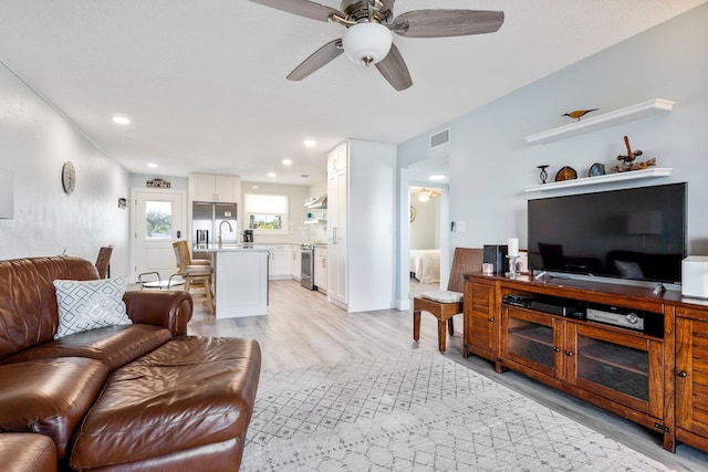 living room featuring ceiling fan, sink, and light hardwood / wood-style floors