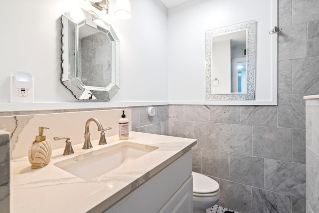 bathroom with vanity, tile walls, and toilet