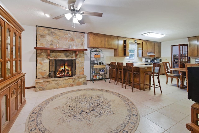 dining room featuring a fireplace, light tile patterned floors, a textured ceiling, and ceiling fan