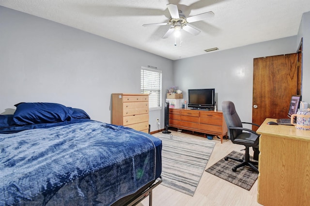 bedroom featuring hardwood / wood-style floors, ceiling fan, and a textured ceiling