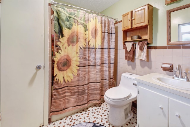 full bathroom with tile patterned floors, a textured ceiling, vanity, tile walls, and toilet