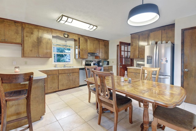 kitchen with hanging light fixtures, light tile patterned floors, stainless steel appliances, and sink