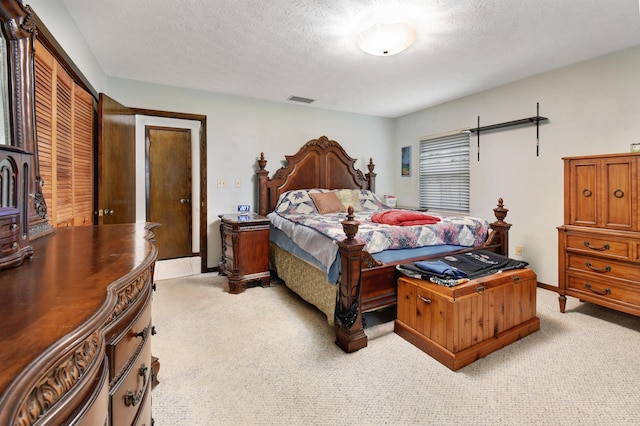 bedroom with a textured ceiling, light carpet, and a closet