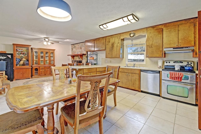 kitchen with ceiling fan, sink, a textured ceiling, light tile patterned flooring, and appliances with stainless steel finishes