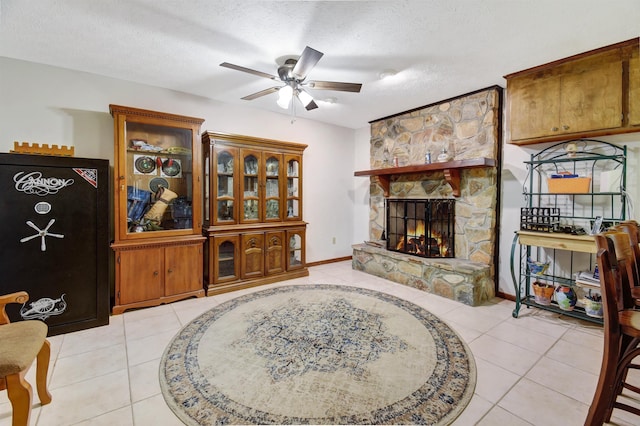 tiled living room with a fireplace, ceiling fan, and a textured ceiling