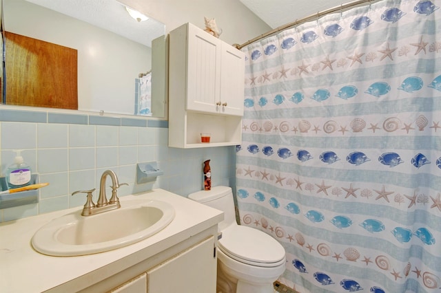 bathroom with vanity, a textured ceiling, toilet, and tile walls