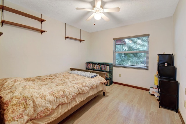 bedroom featuring ceiling fan, a textured ceiling, and light wood-type flooring