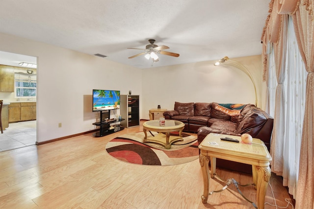 living room with ceiling fan, light hardwood / wood-style floors, and a textured ceiling