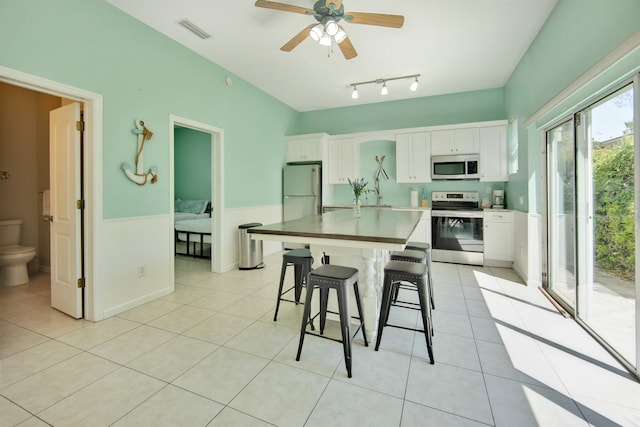 kitchen featuring a center island, white cabinets, a breakfast bar area, ceiling fan, and stainless steel appliances