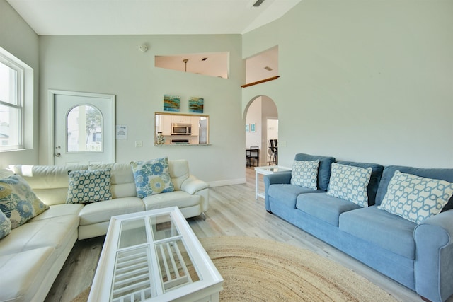 living room featuring a towering ceiling and light hardwood / wood-style flooring