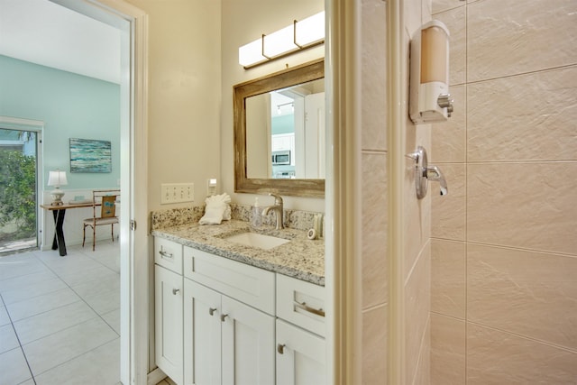 bathroom featuring tile patterned flooring, vanity, and tiled shower