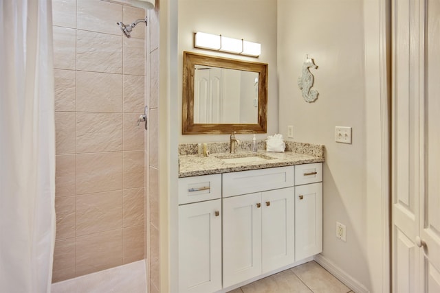 bathroom featuring a tile shower, tile patterned flooring, and vanity