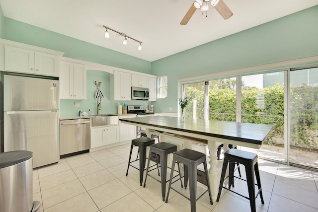 kitchen with appliances with stainless steel finishes, ceiling fan, sink, light tile patterned floors, and white cabinetry