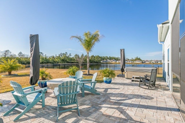 view of patio with a hot tub and a water view