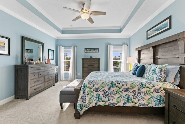 bedroom featuring ornamental molding, light carpet, and a tray ceiling