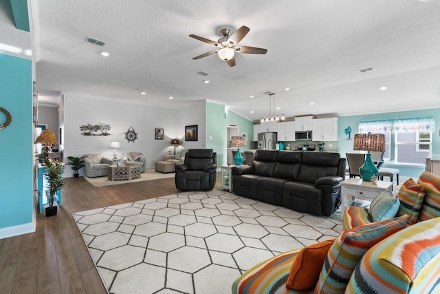 living room with lofted ceiling, ceiling fan, light hardwood / wood-style floors, crown molding, and a textured ceiling