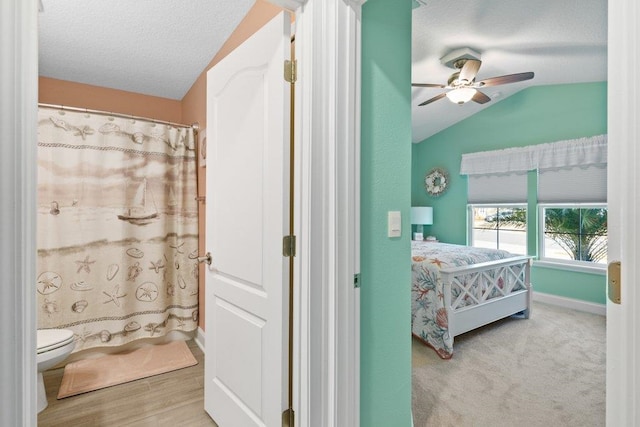 bedroom featuring ceiling fan, lofted ceiling, a textured ceiling, and light hardwood / wood-style flooring