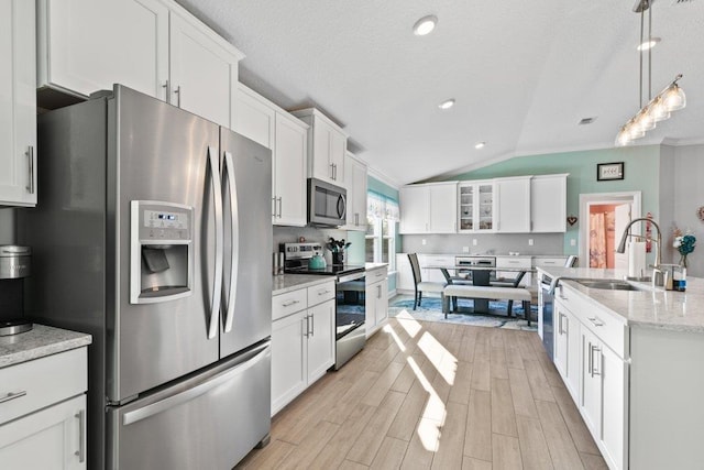 kitchen with sink, appliances with stainless steel finishes, white cabinetry, light stone countertops, and decorative light fixtures