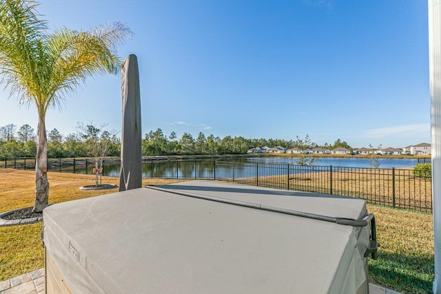 view of home's community with a water view, a hot tub, and a patio