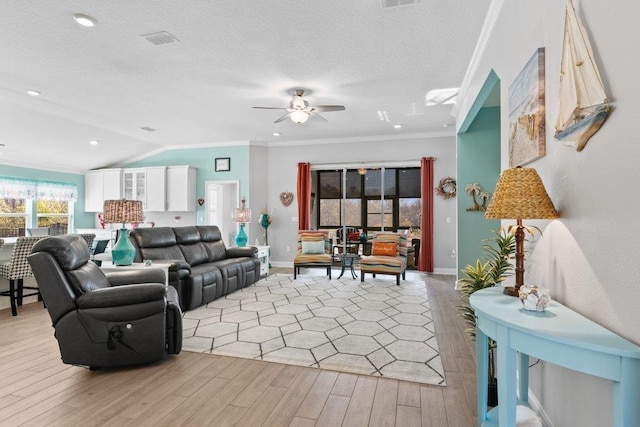 living room with lofted ceiling, crown molding, ceiling fan, light hardwood / wood-style floors, and a textured ceiling