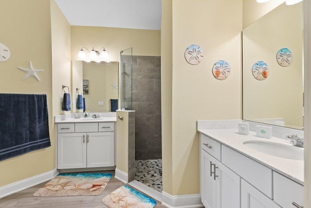 bathroom featuring tiled shower, vanity, and wood-type flooring