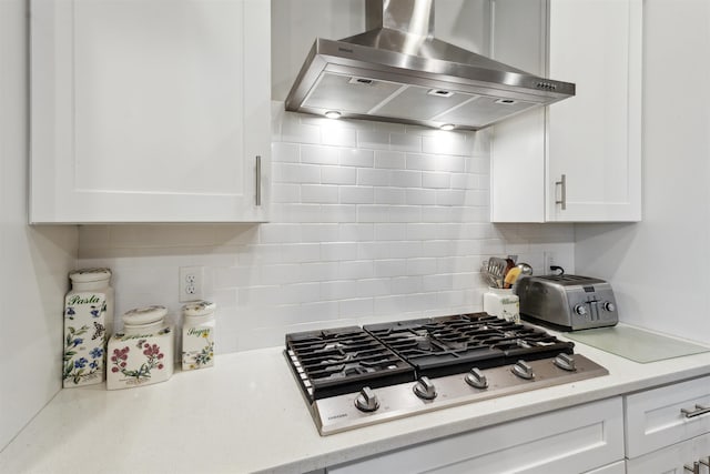 213 Pescado Dr, Saint Augustine, FL 32095 - kitchen with wall chimney exhaust hood, stainless steel gas cooktop, white cabinetry, and tasteful backsplash