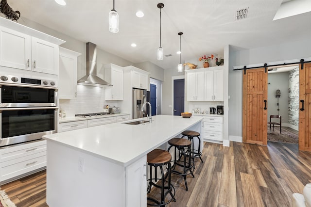 213 Pescado Dr, Saint Augustine, FL 32095 - kitchen with wall chimney range hood, a sink, appliances with stainless steel finishes, a barn door, and backsplash
