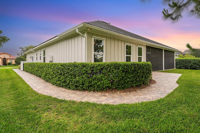 213 Pescado Dr, Saint Augustine, FL 32095 - property exterior at dusk featuring board and batten siding, a yard, a sunroom, and roof with shingles