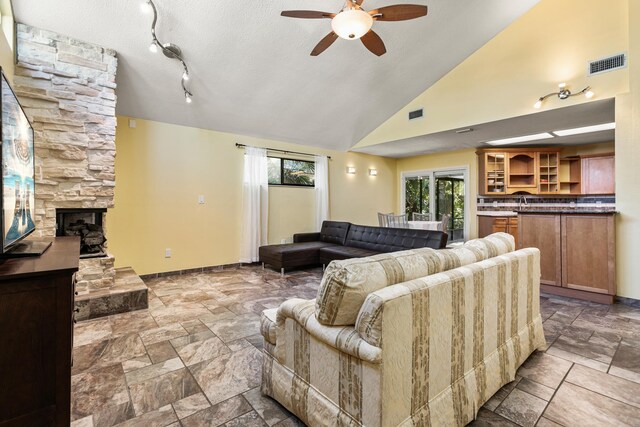 29 Hybiscus Ave, Saint Augustine, FL 32084 - living room featuring ceiling fan, baseboards, stone tile flooring, a fireplace, and a textured ceiling