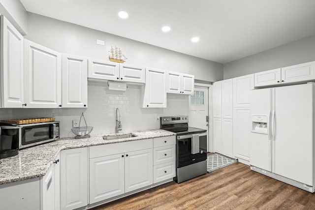 kitchen featuring sink, white cabinets, wood-type flooring, and appliances with stainless steel finishes