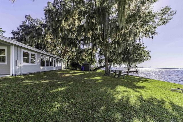 view of yard featuring a water view and a storage shed