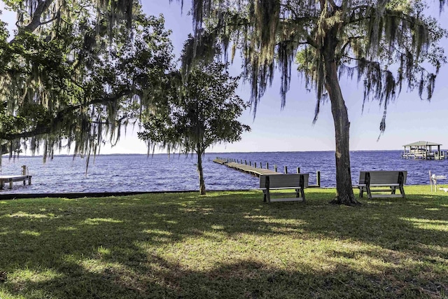 view of property's community with a lawn, a boat dock, and a water view