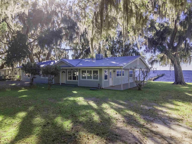 rear view of house with a lawn and a water view