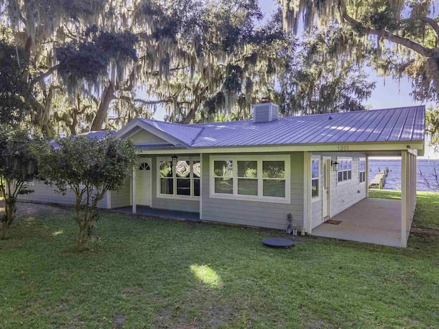 ranch-style house with a front lawn, a water view, and a patio