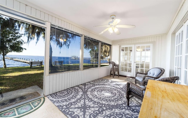 sunroom with ceiling fan and a water view