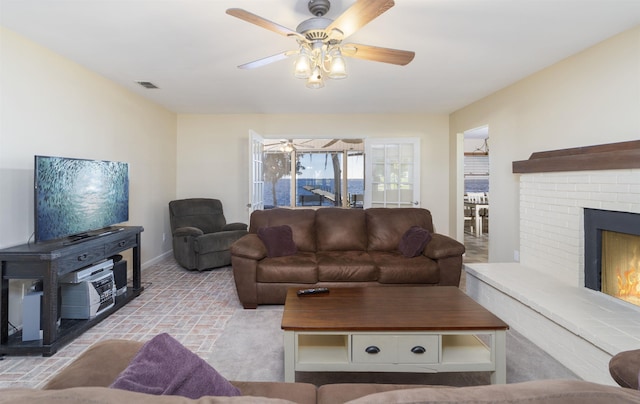 living room featuring ceiling fan and a fireplace