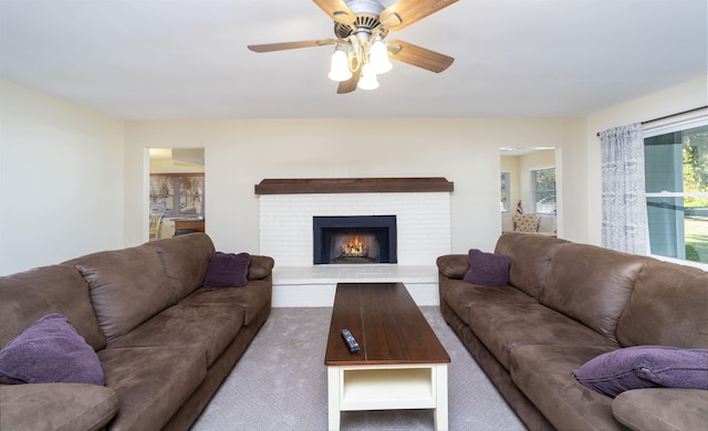 carpeted living room featuring ceiling fan and a fireplace