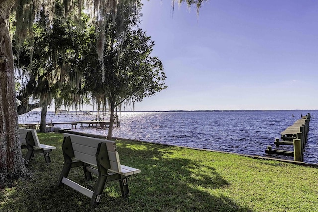 view of dock featuring a water view and a yard