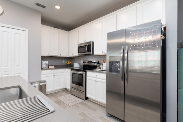 kitchen featuring white cabinets, light wood-type flooring, and stainless steel appliances