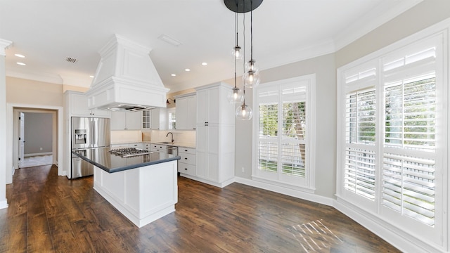 kitchen with custom exhaust hood, white cabinetry, decorative light fixtures, a center island, and stainless steel appliances