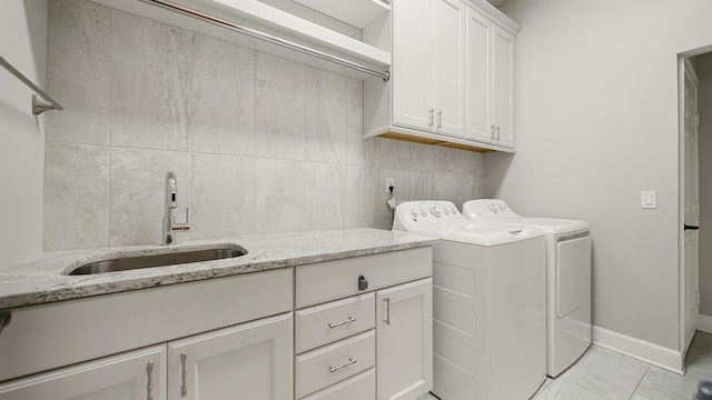 clothes washing area with cabinets, sink, and washer and clothes dryer